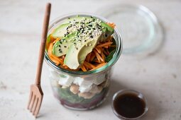 A spinach salad with chickpeas, sheep's cheese, beetroot and avocado with a balsamic honey dressing in a glass