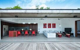 View into modern house with open wall adjoining terrace