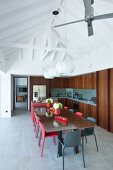 Black and red chairs around dining table in open-plan kitchen