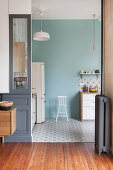 View into kitchen with pale blue wall and patterned cement floor tiles