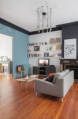 Bücherregal, Fernsehschrank, Polstersofe und Coffeetable im Wohnzimmer mit einer blau-grauen Wand