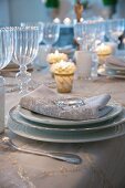 Festive place setting with gold-edged plates, ornate linen napkin and shiny glass pebble