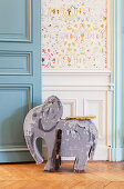 Old wooden elephant toy in front of wainscoting
