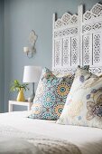 Scatter cushions on white double bed with ornate headboard