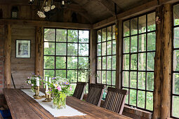 Large wooden table and chairs in rustic orangery with lattice windows