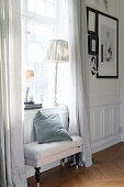 Upholstered bench below window in panelled wall