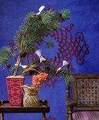 Bird decorations on pine sprigs in front of blue wall with red pattern