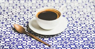 Cup of black Eastern style coffee over oriental bright Moroccan patterned background