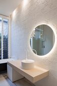 Runder Spiegel vor weißen Wandfliesen mit Struktur in minimalistischem Bad