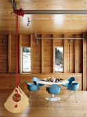 Essbereich mit Klassikermöbeln im Holzhaus mit aufgehängter Designerschaukel