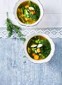 Vegan green minestrone soup with zucchini, cabbage, broccoli, beans and dill (top view)