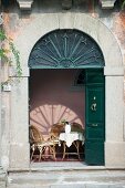 Traditional arched entrance with open, dark-green double doors