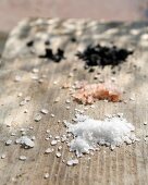 White, pink and black salt on a wooden background