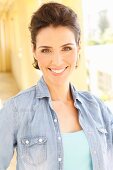 Brunette woman with backcombed hair wearing turquoise top and denim shirt