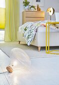 Bodenleuchte im Schlafzimmer mit Doppelbett und gelbem Beistelltisch