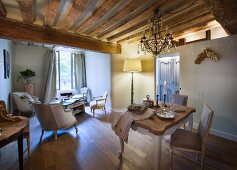 Lit standard lamp and rustic wood-beamed ceiling in dining area with historical ambiance