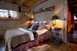 Schlafzimmer im rustikalen Landhausstil mit Tiertrophäen und weihnachtlichem Kerzenlicht