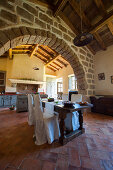 Dining table and brick arch in open-plan, country-house kitchen