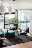 Leather chairs and turquoise ottoman on carpet in lounge with floor-to-ceiling windows