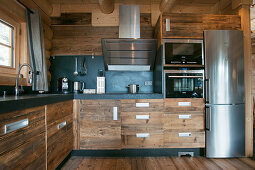 Modern kitchen with rustic wooden cupboards and stainless steel fridge