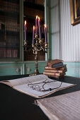 Reading glasses on open, handwritten notebook in front of candelabra