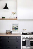 Gas stove next to base cabinet in kitchen with white wood paneling