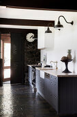 Base cabinets with gray fronts and gas stove in kitchen with slate tiles