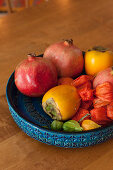 Blaue Schale mit Relief und exotischem Obst in Rottönen