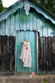 Floral fabric and felt flower hung from clothes hanger on board door of traditional wooden hood
