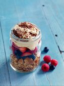 Layered berry trifle with vanilla cream in a glass jar