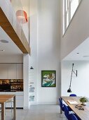 Open-plan kitchen with dining area in high-ceiling room with gallery level