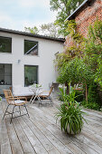 Large terrace in courtyard between house and exposed brick wall