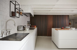 Moderne offene Küche mit weißen Fronten ohne Oberschränke