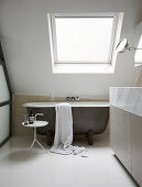 Freistehende Badewanne unter dem Dachfenster mit schiefer Wand