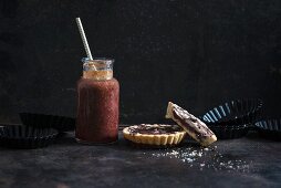 Tartlets filled with sour cherries, vanilla cream and a chocolate glaze, with a red smoothie (vegan)
