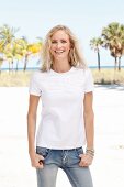Blonde Frau in weißem T-Shirt und Jeanshose am Strand