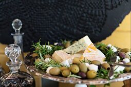 A cheese platter with olives and rosemary
