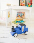 Blaue Spielzeug-Lokomotive auf weißem Dielenboden im Kinderzimmer