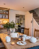 Lit candles on table set for afternoon tea in cottage