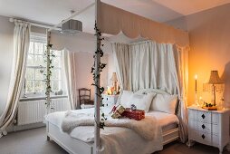 Four-poster bed in white candlelit bedroom