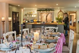 Table set for Christmas dinner in front of island counter in country-house kitchen
