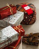 Arrangement mit verpackten Weihnachtsgeschenken, Sitzpouf und Hausschuhen