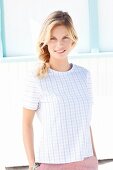 Blonde Frau in kariertem T-Shirt und rosafarbener Hose