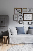 Picture gallery with drawings over the light gray sofa cover