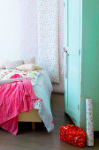 Bett mit geblümter Bettwäsche, Blumentapete und mintgrüner Schrank