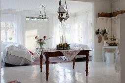 Old table in front of two sofas facing one another covered with throws