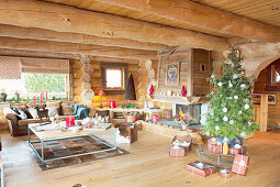 Wohnzimmer mit Weihnachtsbaum und Kaminfeuer im Blockhaus