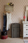 Old suitcases used for storage below vintage dresses hung from coat rack