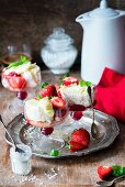 Coconut meringue rolls, sliced and served with strawberries in dessert glasses