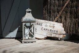 Candle lantern next to piece of driftwood with lettering